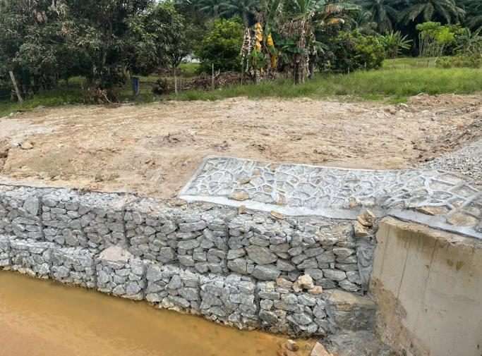 Completed gabion retaining wall stabilising a road embankment
