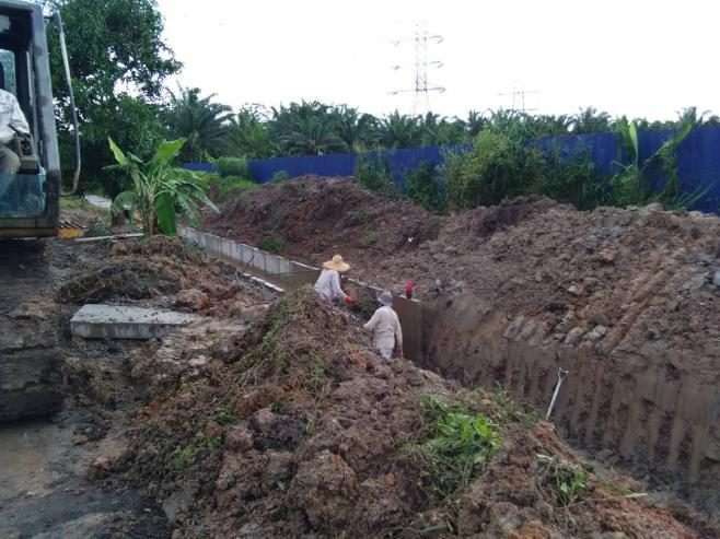 Concrete pipes and manhole rings beside an open sewerage trench